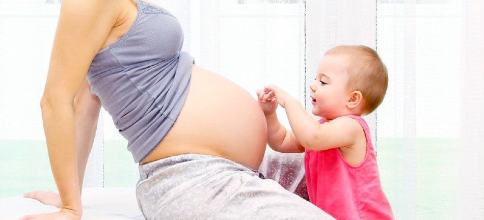 Young pregnant mother and baby girl, playing at home, happy family concept?