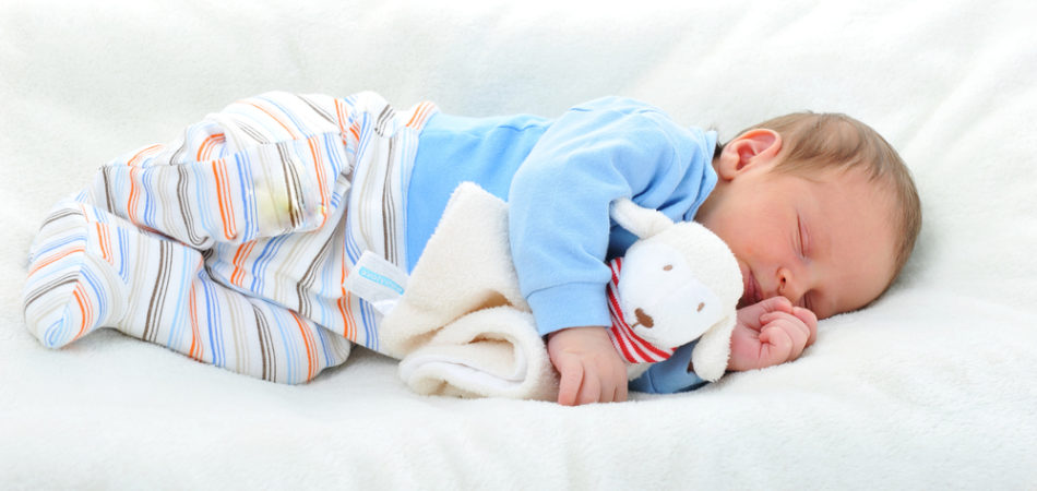 cute baby with toy sleeping on white blanket