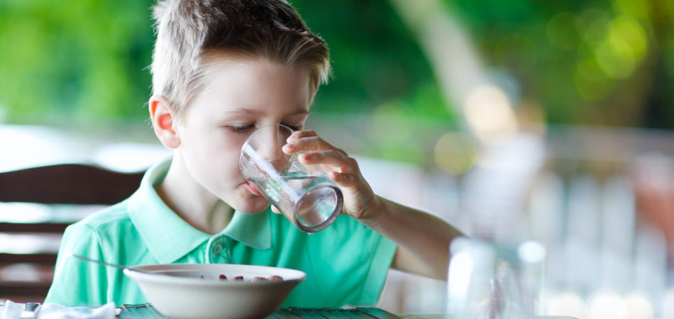Cute little boy at restaurant drinking water