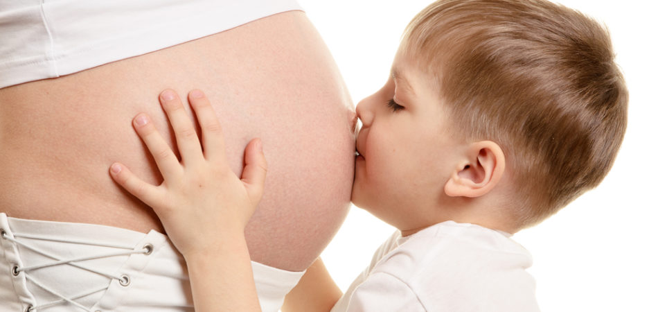 Young boy is kissing the pregnant woman isolated on white background