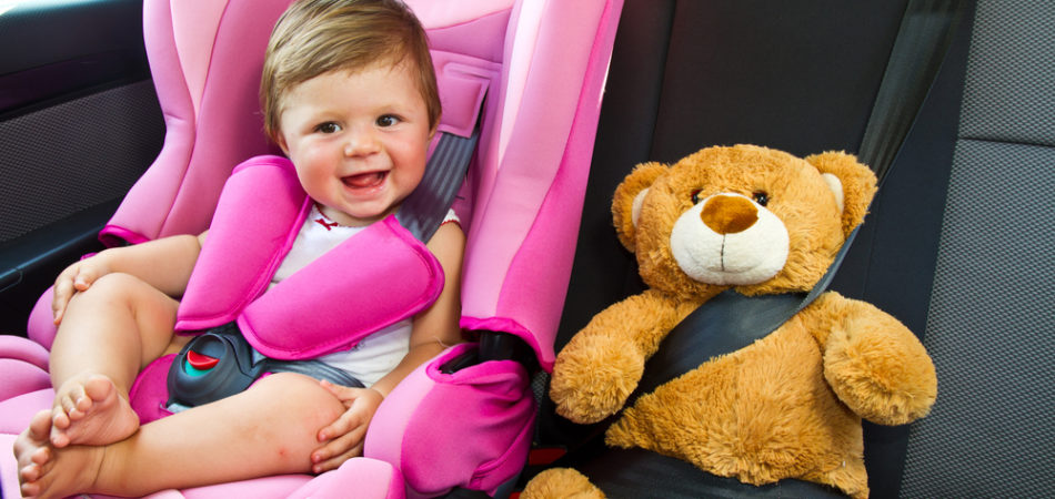 Baby girl with his teddy bear smile in car