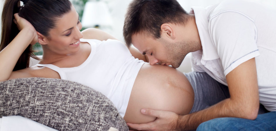 Future dad kissing belly of his pregnant wife