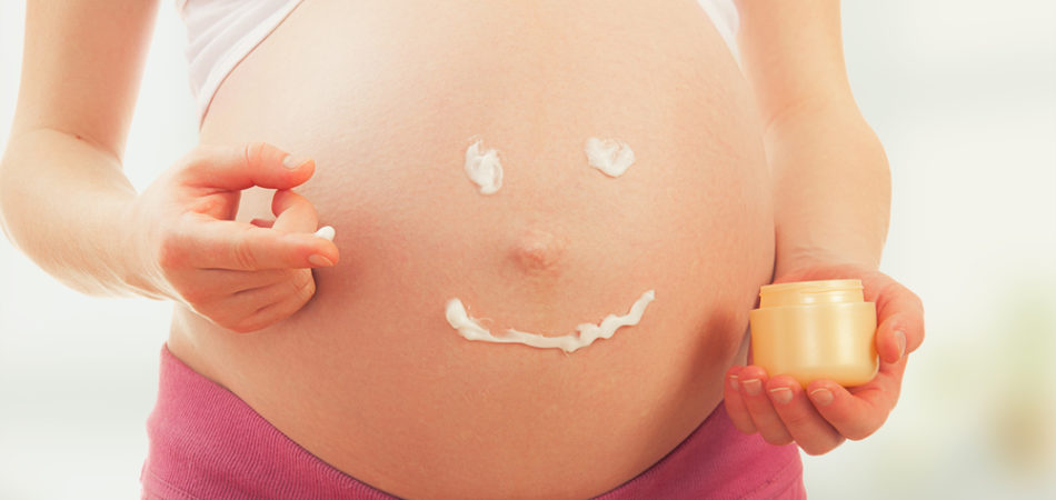 pregnancy and skin care. belly of pregnant woman and smile from moisturizing cream for stretch marks