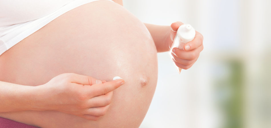 concept of pregnancy and skin care. belly of pregnant woman  and moisturizing cream for stretch marks