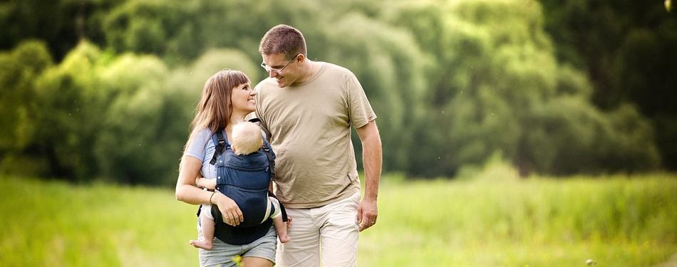Family walking in the field with baby in the baby carrier