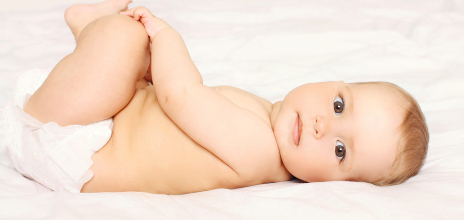 Portrait of cute baby in diapers lying on the bed at home