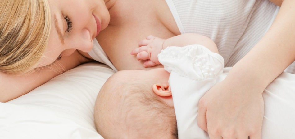 Young mother breastfeeds her baby. Breast-feeding.