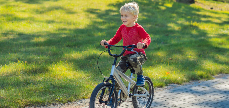 Happy kid boy of 5 years having fun in the park with a bicycle on beautiful day. BANNER, LONG FORMAT