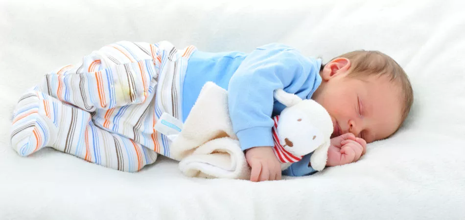 cute baby with toy sleeping on white blanket